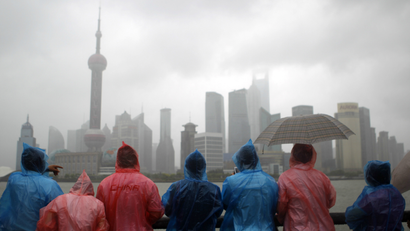 People looking at the Shanghai skyline during a rainstorm.