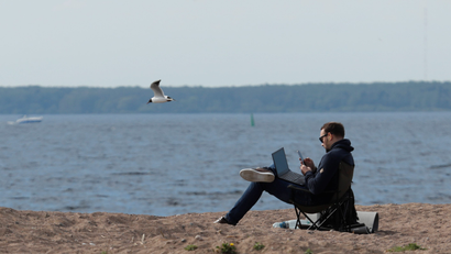 A person sitting on a beach with their laptop and computer.