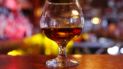 A glass of cognac on a bar.