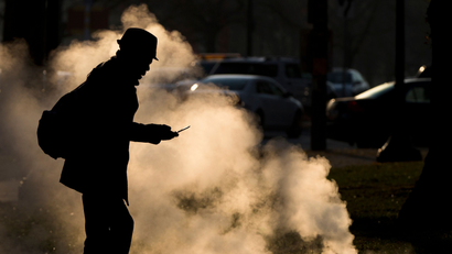 FILE - In this Nov. 30, 2012 file photo, a pedestrian looks at his phone near steam vented from a grate near the Philadelphia Museum of Art on a cold morning in Philadelphia. Every time a person shops online or at a store, loyalty cards linked to phone numbers or email addresses can be linked to other databases that may have location data, home addresses and more. Voting records, job history, credit scores (remember the Equifax hack?) are constantly mixed, matched and traded by companies in ways regulators haven’t caught up with. (AP Photo/Matt Rourke, File)