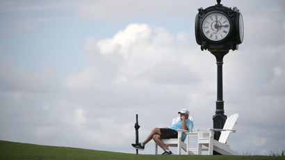 A spectator watches golf under a cloc