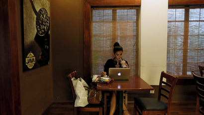 Woman drinks coffee while working on her laptop at Java Lounge coffee shop in Colombo
