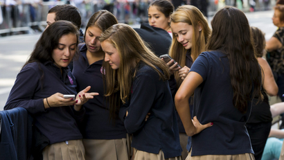Teenage girls look at a phone