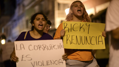 Demonstrators holding signs that read in Spanish "Corruption is violence" and "Ricky renounce",