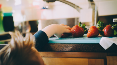 A child reaches for a strawberry