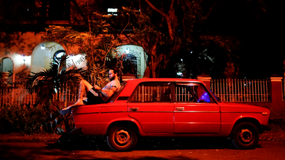 Tourist guide Daniel Hernandez, 26, sits on his Russian-made car as he speaks to his girlfriend who lives in Britain, at an internet hotspot in Havana, Cuba, September 24, 2017.