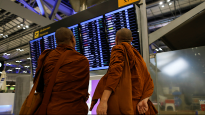 Monks look at airport departure board