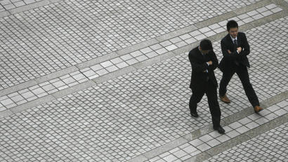 Businessmen walk though a square in Tokyo