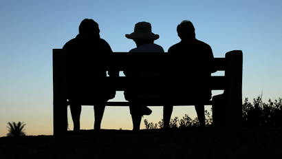 Elderly people sit on a park bench after sun set in Encinitas