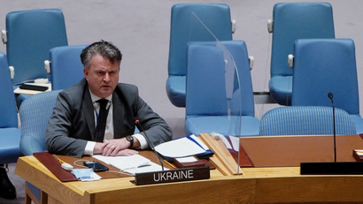 Ukrainian Ambassador to the United Nations sits at a desk with Ukraine's placard displayed in front of him.