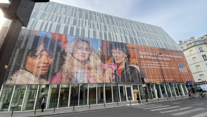 The headquarters of La Banque Postale in Paris resembles a greenhouse, with a billboard advertising the bank's climate policy.