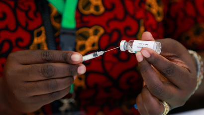 A Nigerian health worker is takes a dose of the COVID-19 vaccine from a vial