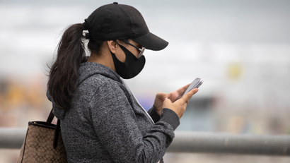 A woman wears a face masks as she views her mobile phone during the global outbreak of the coronavirus disease