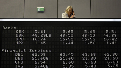 A woman takes some notes as she stands on the gallery over share prize index boards at the German stock exchange in Frankfurt,