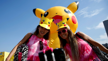 Women take a selfie in front of a large Pikachu figure at a Pokemon Go Park event in Yokohama
