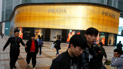 People walk past a Prada luxury fashion boutique near Wangfujing Street, a pedestrianised shopping area, in Beijing, China
