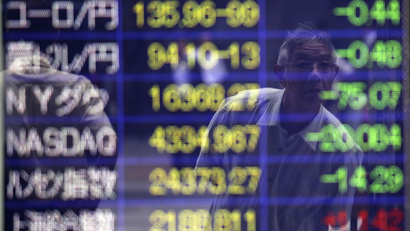 A man checking the stock prices is reflected on an electronic stock board of a securities firm in Tokyo Friday, Aug. 8, 2014. Asian stocks sank Friday as jitters over the crises in Iraq and Ukraine escalated but Chinese stocks rose after trade figures showed surprisingly strong growth in exports. In Japan, the 225-issue Nikkei Stock Average dived 454.00 points, or 2.98 percent, and finished at 14,778.37, hitting a two-month low. (AP Photo/Eugene Hoshiko)