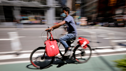 A rider for "Grubhub" food delivery service rides a bicycle during a delivery in midtown Manhattan in New York