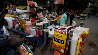 A vendor sells groceries to a customer at his roadside shop in New Delhi