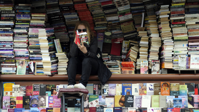 A woman reads a book at her open air book store in Skopje
