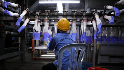 A worker inspects newly-made gloves at Top Glove factory in Shah Alam, Malaysia
