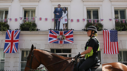 A police officer on horseback, rides past a cutout of Prince Harry and Meghan Markle, ahead of their wedding.
