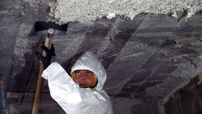 A worker scrapes asbestos from a school ceiling in France.