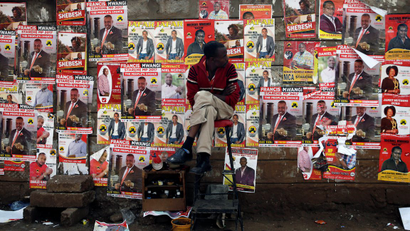 A man looks at campaign posters as he waits to cast his ballot, during the Jubilee Party primary elections, outside a polling centre in Nairob
