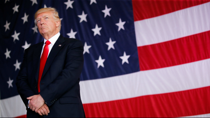 U.S. President Donald Trump stands in front of a U.S. flag