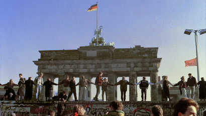 Berliners sing and dance on top of The Berlin Wall to celebrate the opening of East-West German borders in this Nov. 10, 1989 file picture. Thousands of East German citizens moved into the West after East German authorities opened all border crossing points to the West. In the background is the Brandenburg Gate. Built in 1961 of barbed wire and concrete, the wall divided Berlin, becoming the most powerful symbol of The Cold War. Thursday, Nov. 9, 2006 marks the 17th anniversary of the fall of the Berlin Wall. (AP Photo/Thomas Kienzle, File)