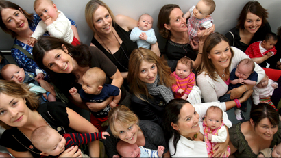 Around twenty mothers and their babies pose together for pictures at King's College Hospital in London.