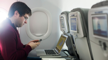 A man uses his mobile phone and laptop to test a new high speed inflight Internet service named Fli-Fi while on a special JetBlue media flight out of John F. Kennedy International Airport in New York