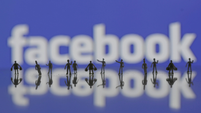 Photo illustration of 3D-printed models of people in front of a Facebook logo