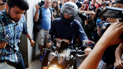 Outgoing Greek Finance Minister Yanis Varoufakis tries to leave on his motorcycle surrounded by media, after his resignation in Athens, Monday, July 6, 2015. Greece and its membership in Europe's joint currency faced an uncertain future Monday, with the country under pressure to reach a bailout deal with creditors as soon as possible after Greeks resoundingly rejected the notion of more austerity in exchange for aid.