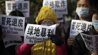 Dozens of homeowners protest outside the headquarters of a Chinese property developer over discounts that came after they paid for their own apartments in Shanghai, China, on Friday, Dec. 16, 2011. The government has said it will keep policies aimed at cooling the property market in place to help bring prices down to more affordable levels, but news that first-time homeowners may be allowed lower-interest mortgages may signal an easing for real estate developers stressed by tight credit and falling sales. (AP Photo/Eugene Hoshiko
