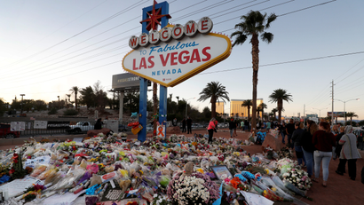 The "Welcome to Las Vegas" sign is surrounded by flowers and items, left after the October 1 mass shooting, in Las Vegas