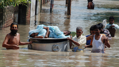 An ailing woman is carried on top of a cooking pot through flood waters after heavy monsoon rains in the northern Indian city of Vrindavan September 25, 2010. India's monsoon is likely to start receding by early October, the weather office said on Thursday, limiting the risk of crop damage from floods in the north that could be triggered if unusual heavy rains persist. REUTERS/K. K. Arora