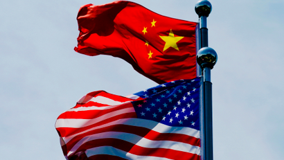 A Chinese flag and American flag wave in the wind.