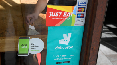 Signage for Just Eat is seen next to Uber Eats and Deliveroo advertisements on the window of a restaurant in London, Britain, August 5, 2019.