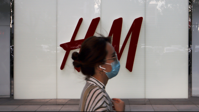 A woman walks past a store of H&M.
