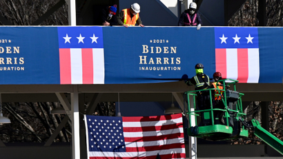 Workers place Biden-Harris inauguration banners on the inaugural parade viewing stand.