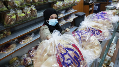 A vendor wearing a face mask arranges bread inside a Beirut bakery