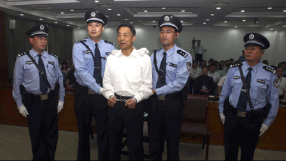 In this photo released by the Jinan Intermediate People's Court, fallen politician Bo Xilai, center, is handcuffed and held by police officers as he stands at the court in Jinan, in eastern China's Shandong province Sunday, Sept. 22, 2013. The Chinese court convicted Bo on charges of taking bribes, embezzlement and abuse of power and sentenced him to life in prison, capping one of the country's most lurid political scandals in decades. (AP Photo/Jinan Intermediate People's Court)