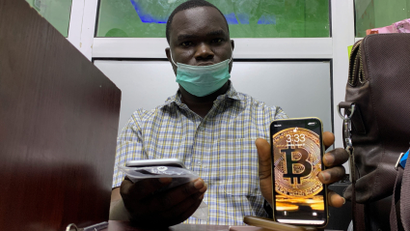 Abolaji Odunjo, a gadget vendor who trades with bitcoin, poses with his mobile phone after an interview with Reuters at his store at the '"Computer village", in Lagos