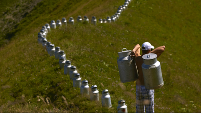A volunteer carries milk churns as he helps land art artist Gerard Benoit a la Guillaume to form an art installation at the Chenau de Mayen in the resort of Leysin, Switzerland August 7, 2015. More than 80 milk churns were placed between the Tour d'Ai and the Tour de Mayen summits at an altitude of 2,000 meters (6,561 feet) above sea level under the direction of the artist, to be photographed for his ongoing art project entitled "Milk churns without borders". REUTERS/Denis Balibouse