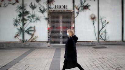 A woman wearing a protective face mask walks past the closed Dior shop on the Champs Elysees Avenue in Paris