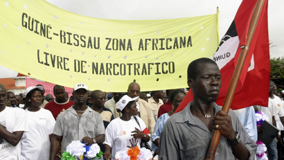 A crowd of people carrying a flag demonstrate against drug trafficking in Guinea-Bissau