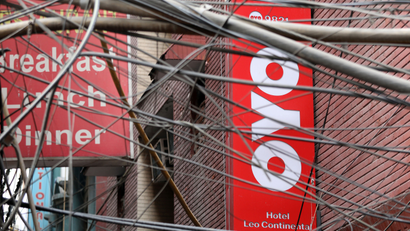 The logo of OYO, India's largest and fastest-growing hotel chain, installed on a hotel building is seen through wires in an alley in New Delhi