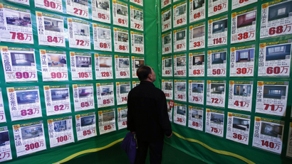 A man looks at posters on a giant advertising board showing information on second-hand apartments at a real estate exhibition in Shenyang, Liaoning province April 17, 2014. China's real estate investment rose 16.8 percent in first three months of 2014 from a year earlier, and revenues from property sales dropped an annual 5.2 percent, the National Bureau of Statistics said on Wednesday. REUTERS/Stringer china housing market home sales prices sales financial crisis gdp