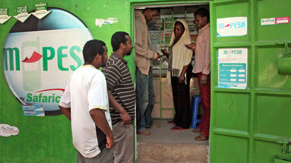 In this photo of Wednesday Aug. 24, 2011 customers make money transfers at an M-Pesa counter in Nairobi, Kenya, as others wait outside. A mobile phone banking service called M-Pesa allows people without a bank account to transfer money between phones instantly anywhere in the country. More than 50 countries now have such services, including Afghanistan. The fundraising effort Kenyans for Kenya has raised more than $7 million for drought victims. Bob Collymore, the head of telelphone company Safaricom, said more than 86 percent of early donations to the campaign came through M-Pesa.
